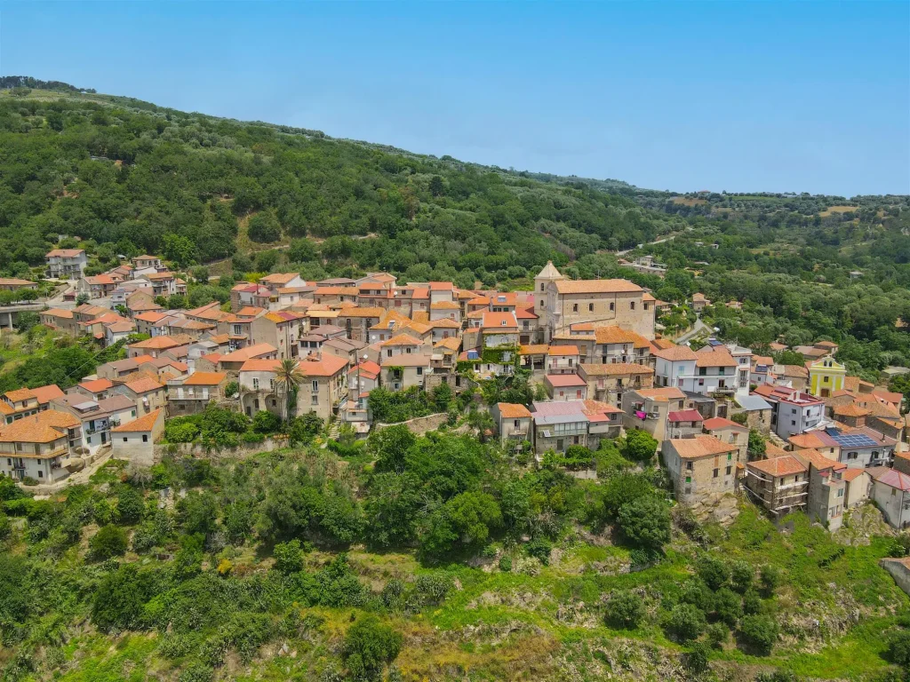 Veduta aerea del borgo medievale di Motta Filocastro, in Calabria, circondato da colline e uliveti secolari.